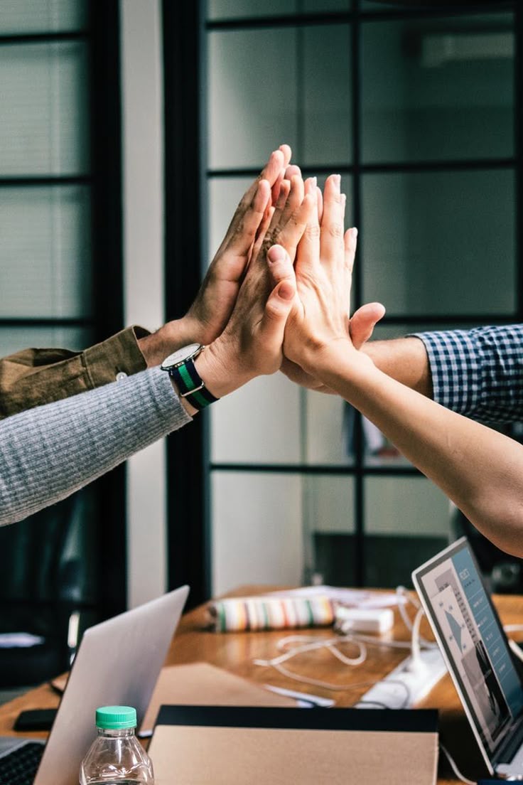 Colleagues bringing their hands together over a shared workspace