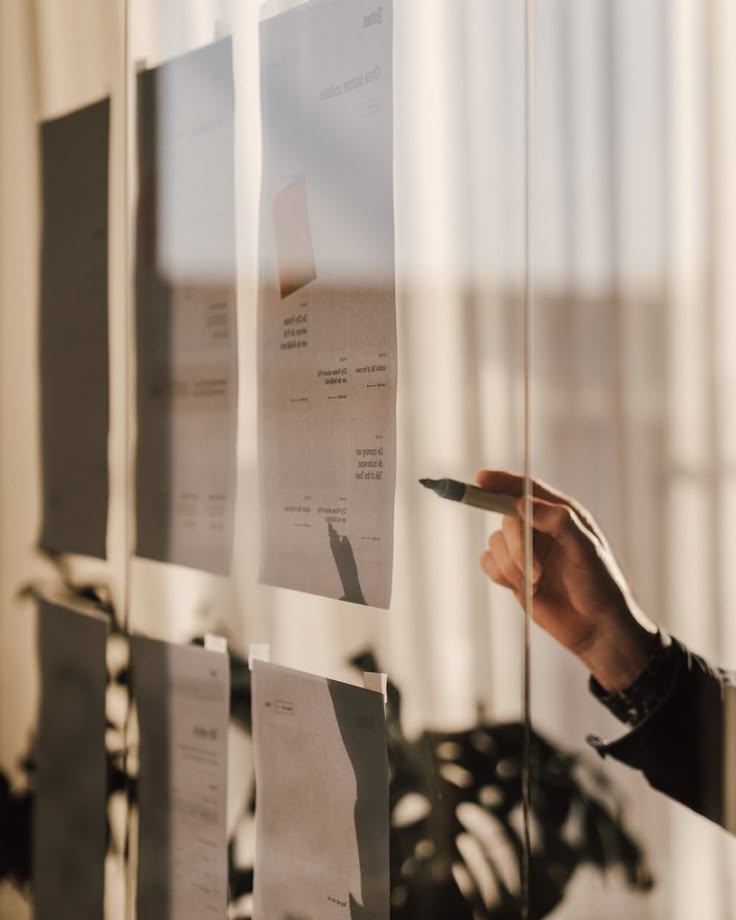 A person reviewing documents on a glass planning board